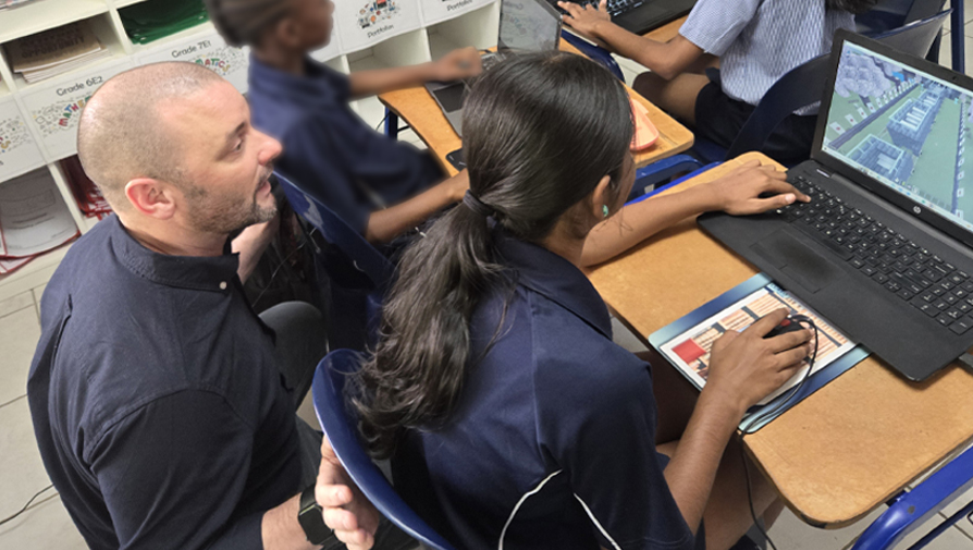 faculty and kid looking at a game on a laptop